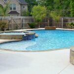 Family enjoying a cool stamped concrete pool deck on a sunny day with reflective surfaces.